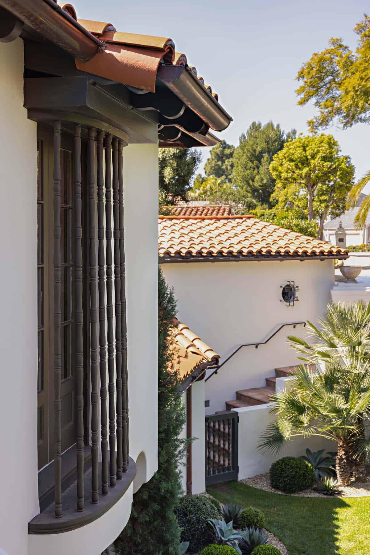 Curved bay window with turned wood spindles beneath a clay tile roof