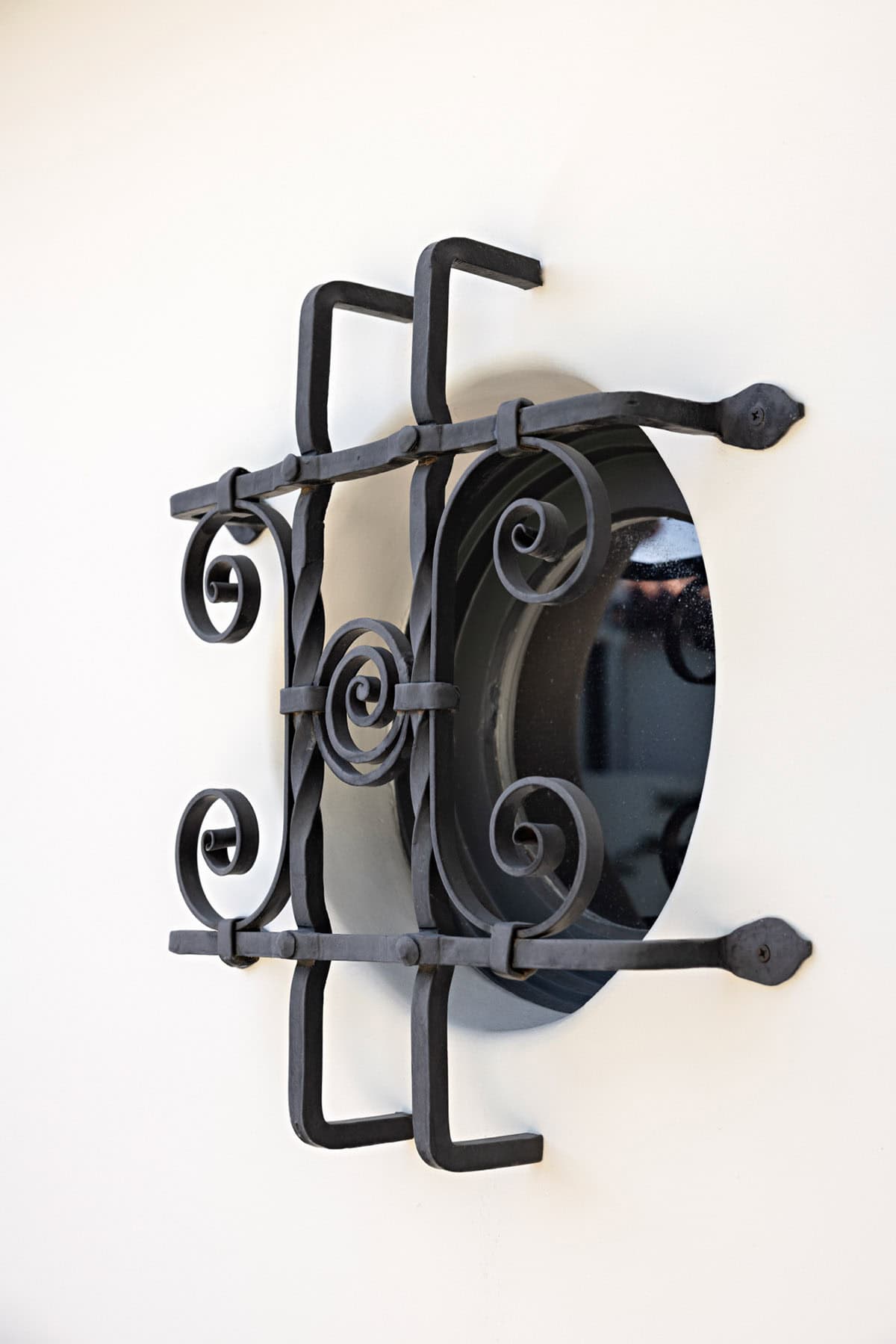 Wrought iron grille over a round window on a white stucco wall