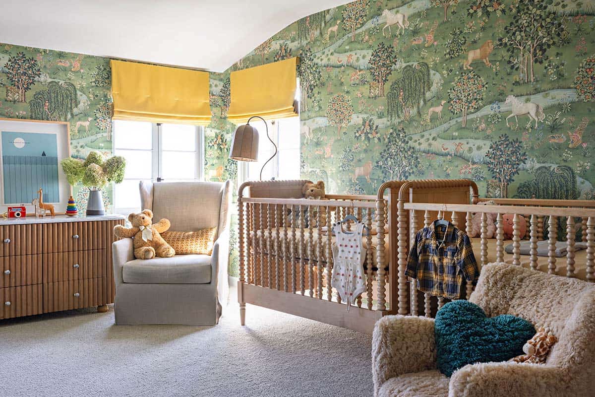 Nursery with animal wallpaper, spindle cribs, and yellow roman shades