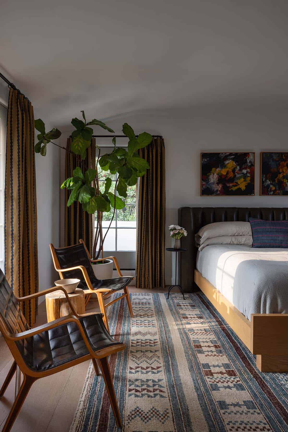 Guest bedroom with leather headboard, striped curtains, and leather sling chairs