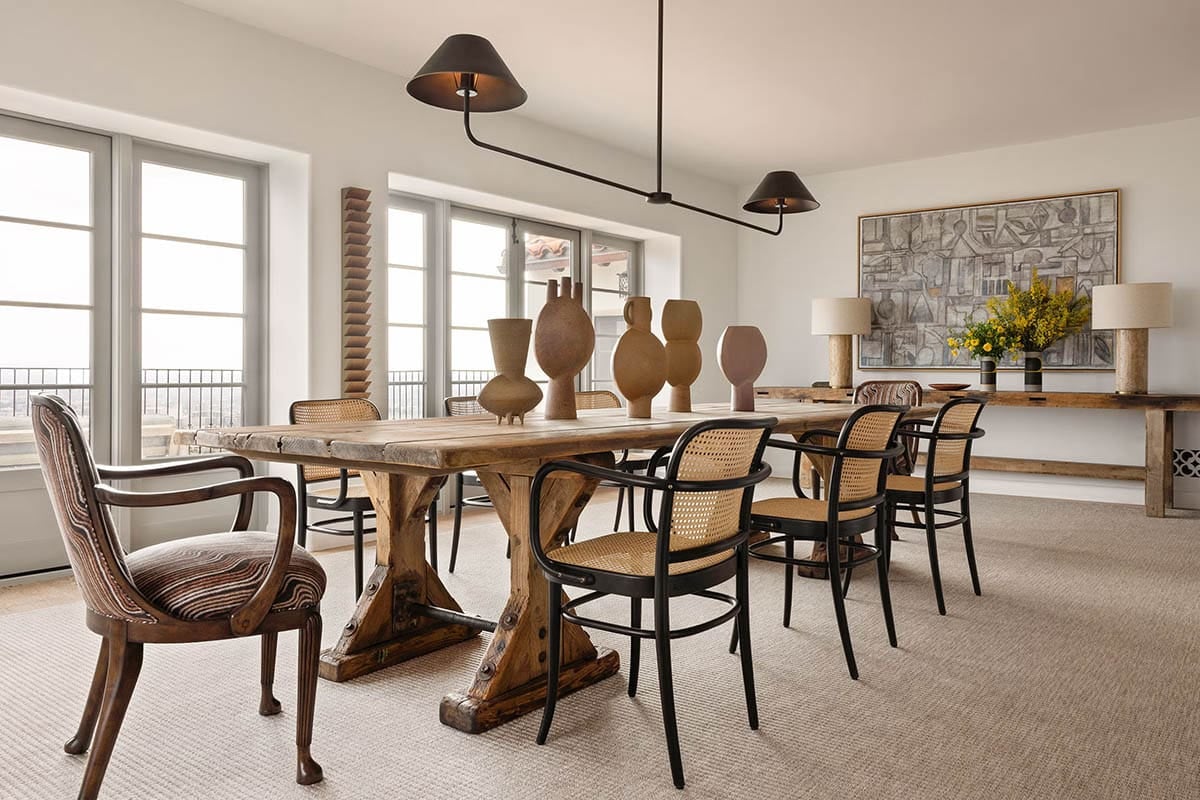 Dining room with rustic trestle table, cane chairs, and ceramic vases