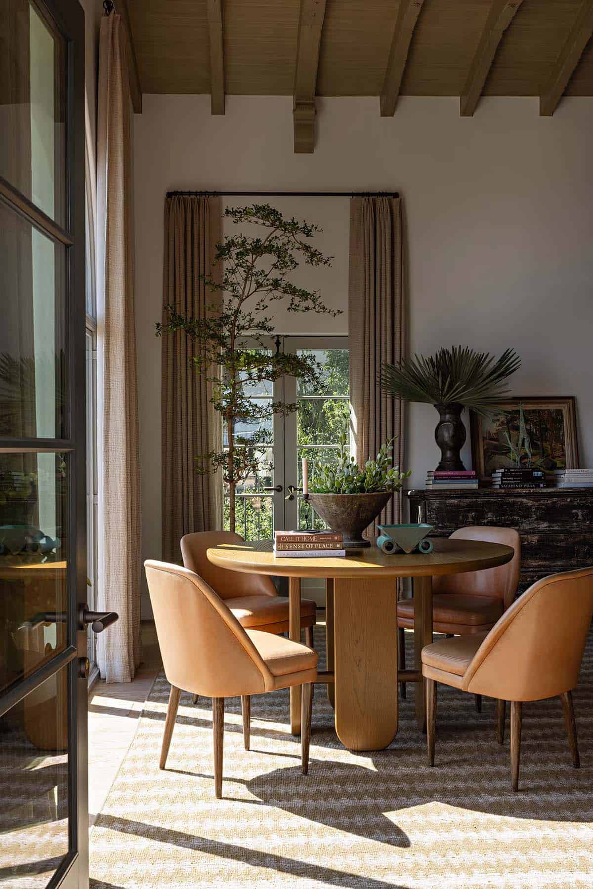 Living room with round oak table, leather chairs, and beamed ceiling