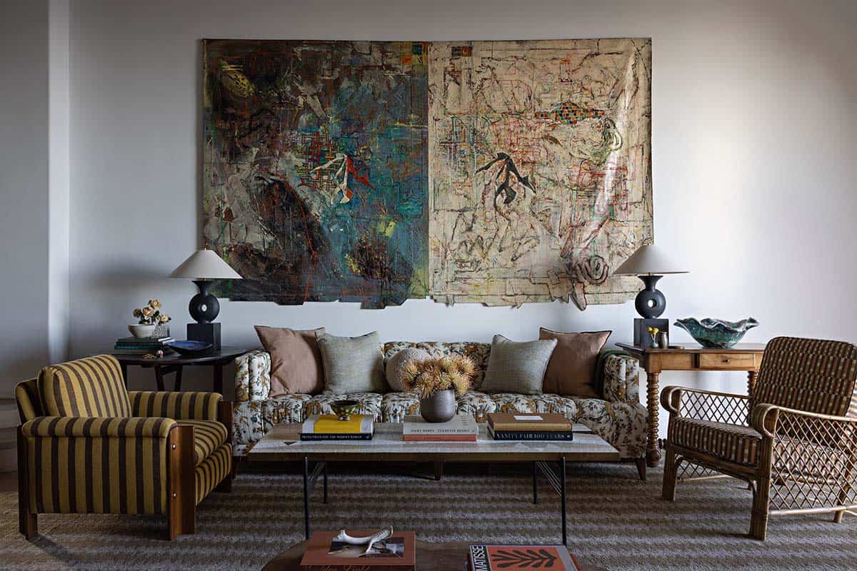 Sitting area with large abstract artwork, floral sofa, and striped armchair