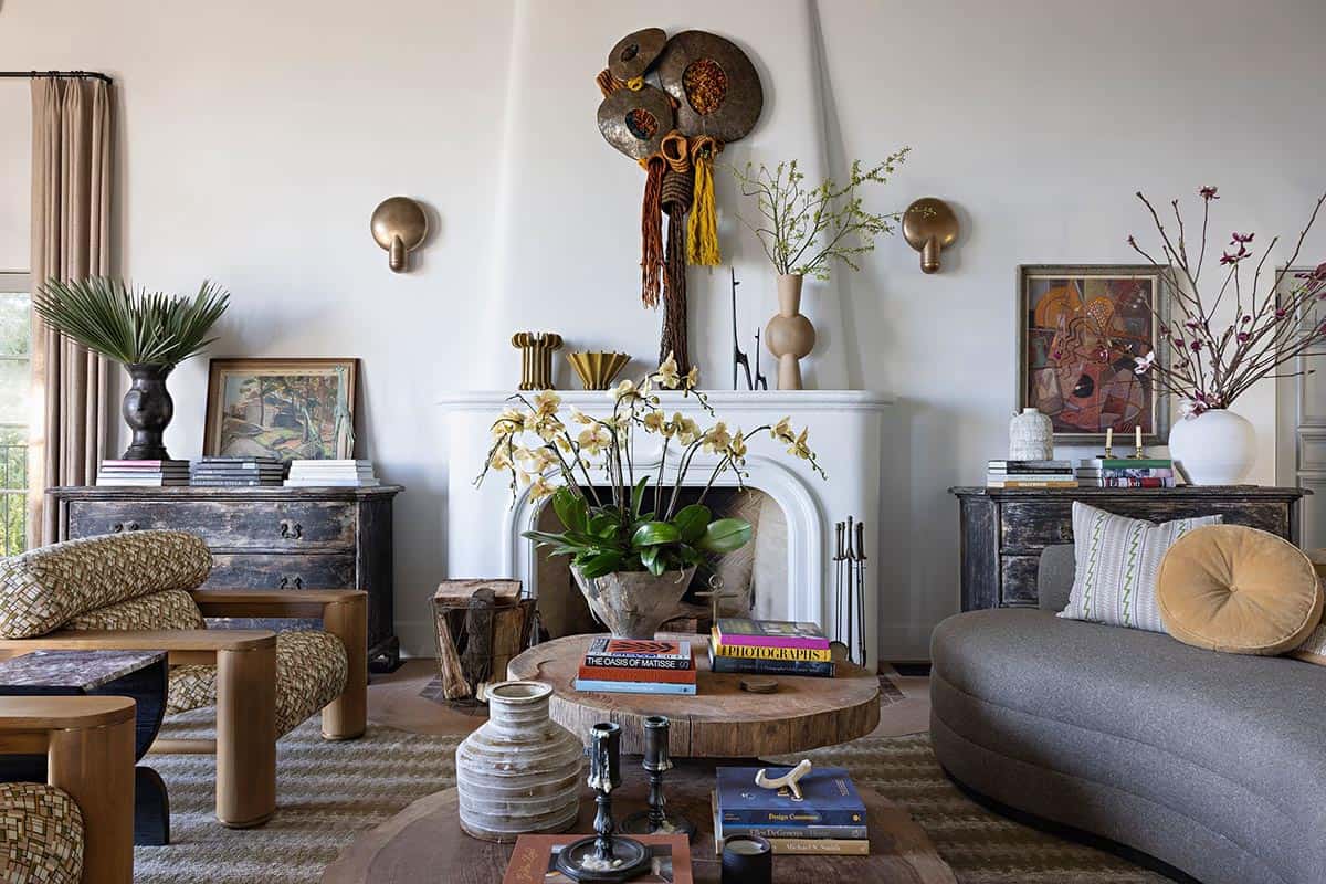 White plaster fireplace with eclectic mantel decor and distressed wood chests