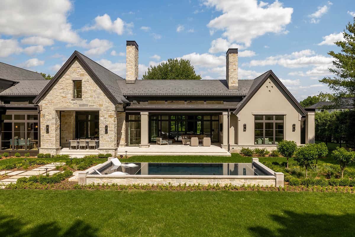 Backyard facade with twin chimneys overlooking raised pool and lawn