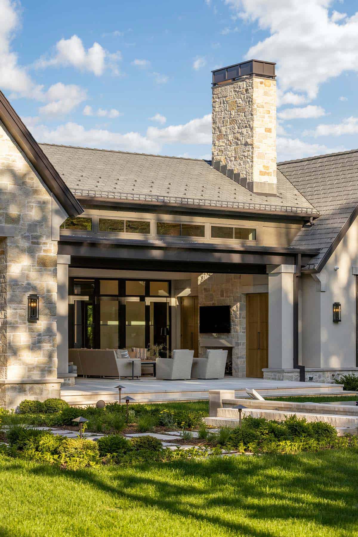 Stone chimney rising above covered patio with lounge seating