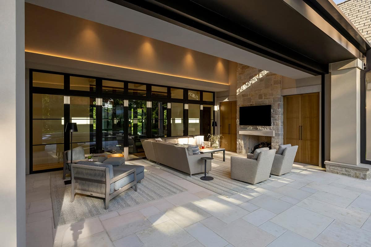 Outdoor living room with stone fireplace and wood-beam ceiling