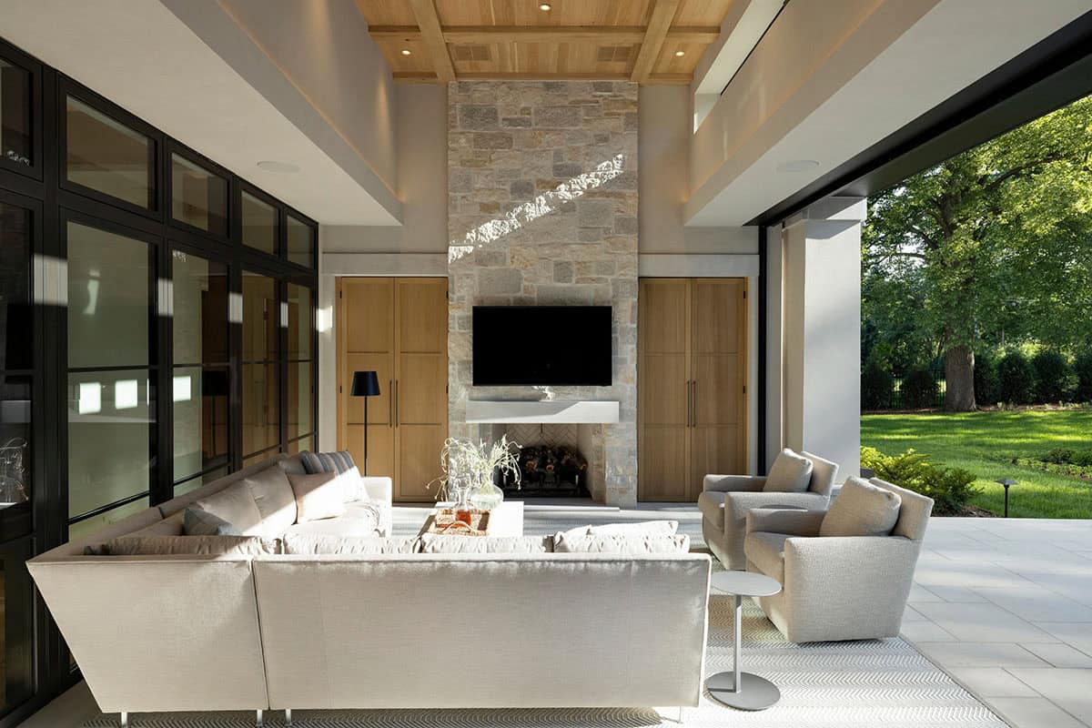 Covered patio seating area with stone fireplace and wood cabinetry