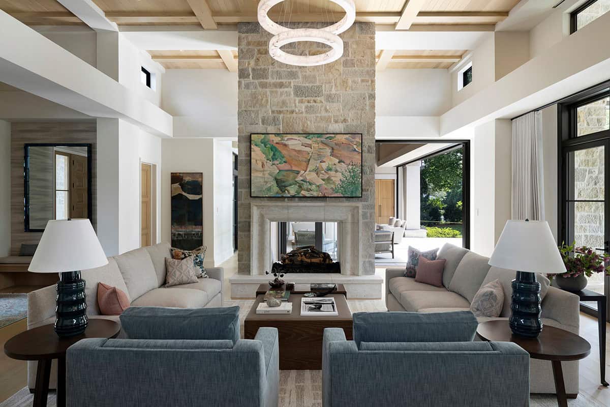 Living room with double sofas facing stone fireplace and art