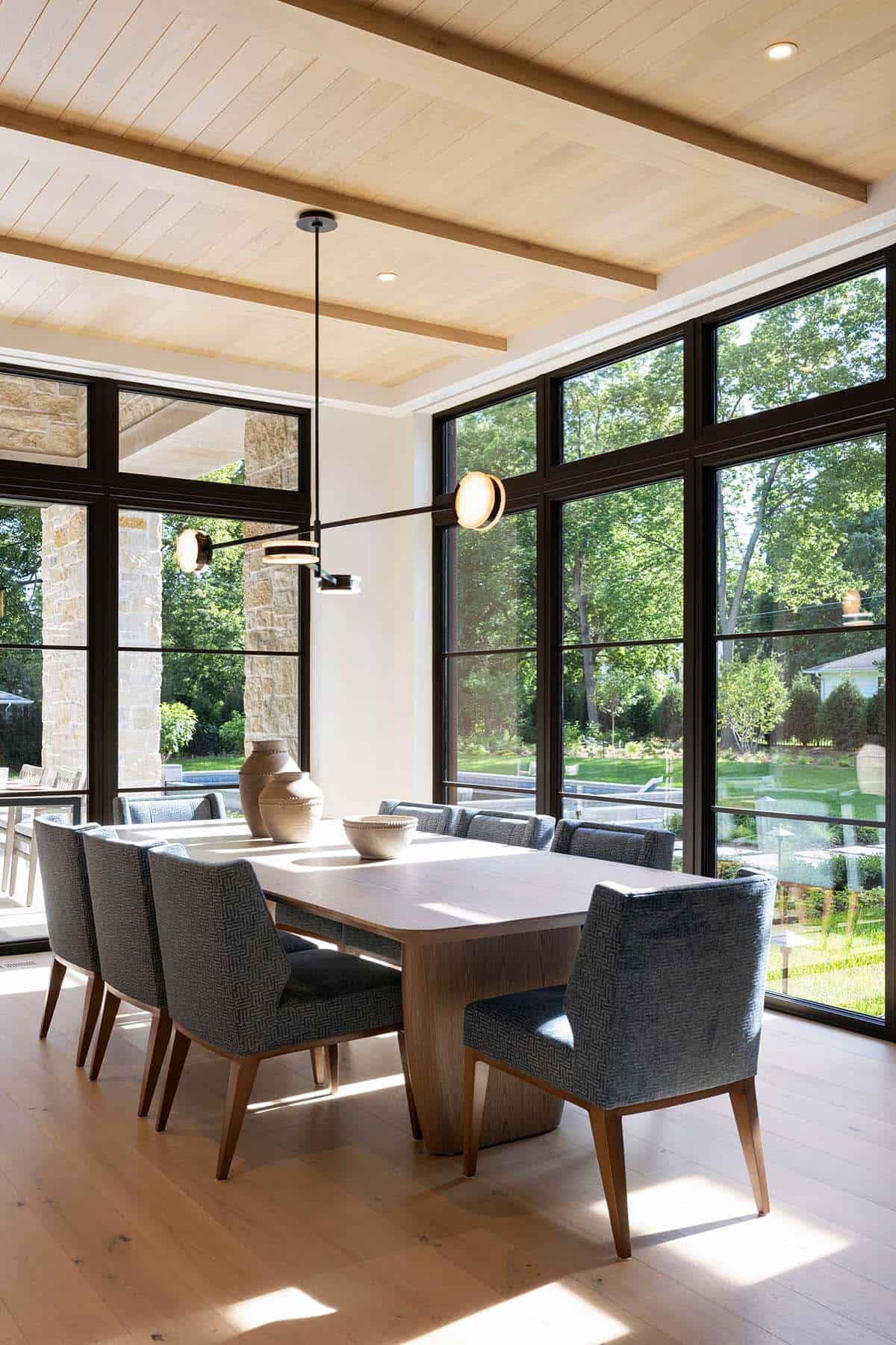 Dining room with wood ceiling beams and floor-to-ceiling black windows