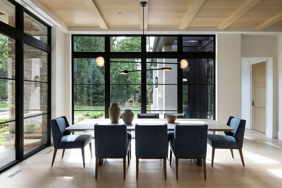 Dining table with sculptural pendant light beneath vaulted wood ceiling