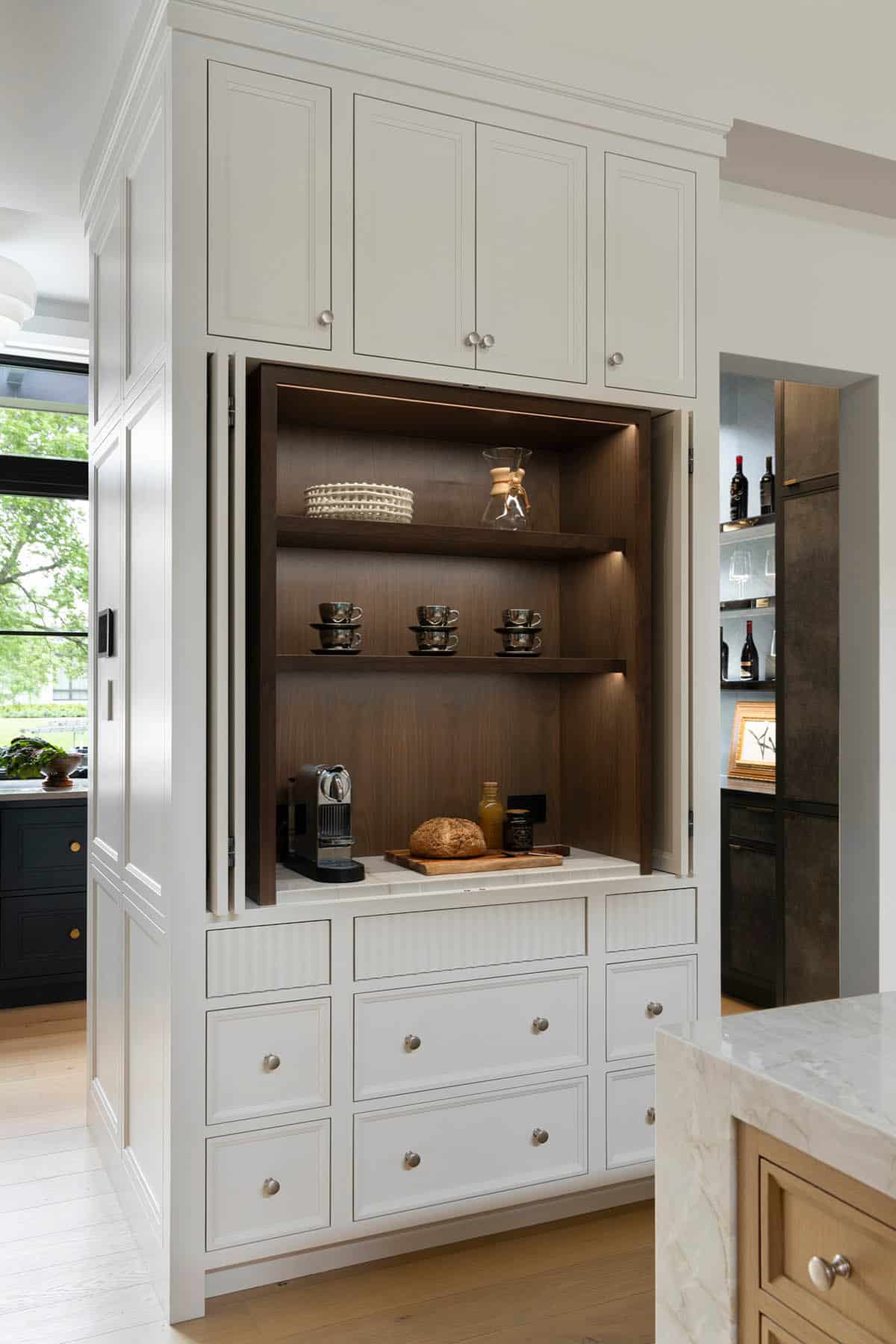 Hidden coffee station with walnut interior behind folding cabinet doors