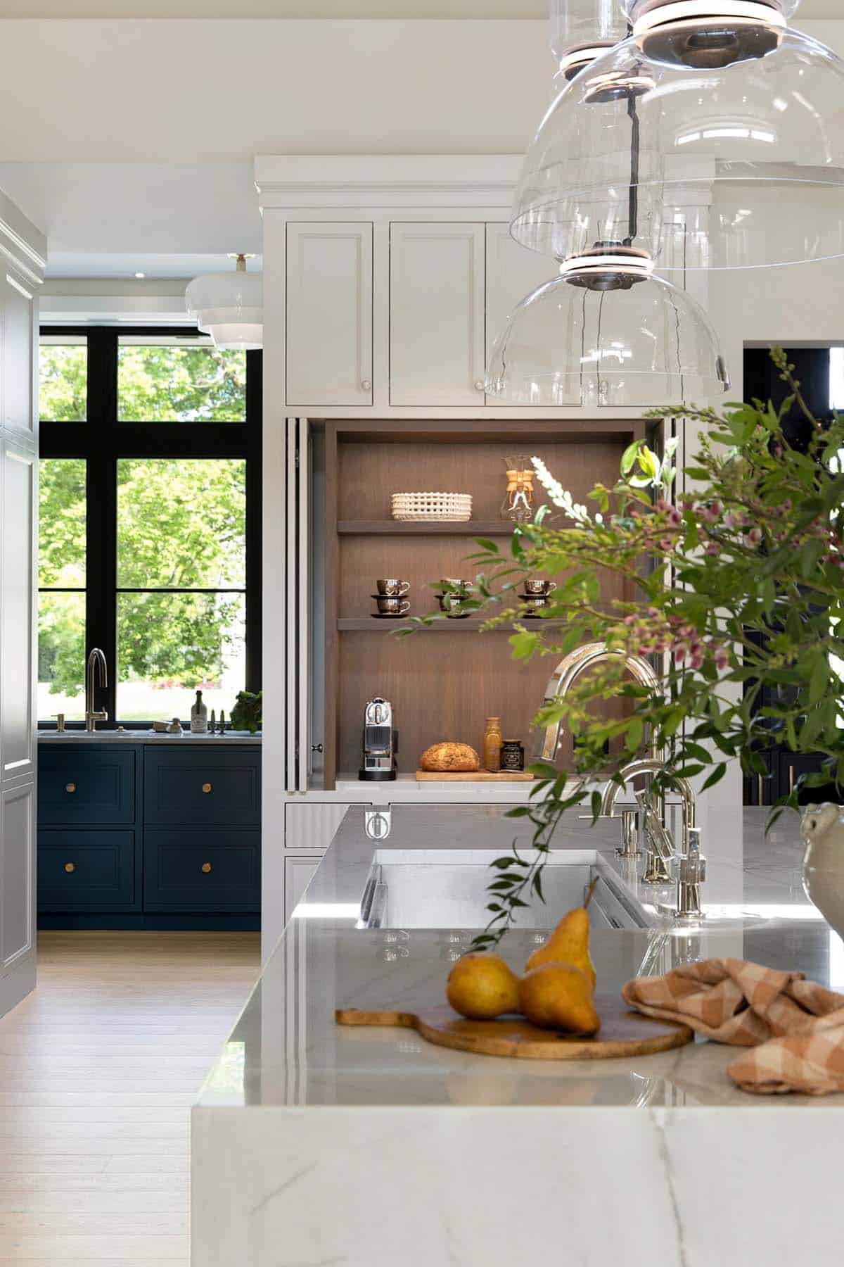 Kitchen island with hidden coffee nook and navy cabinetry beyond