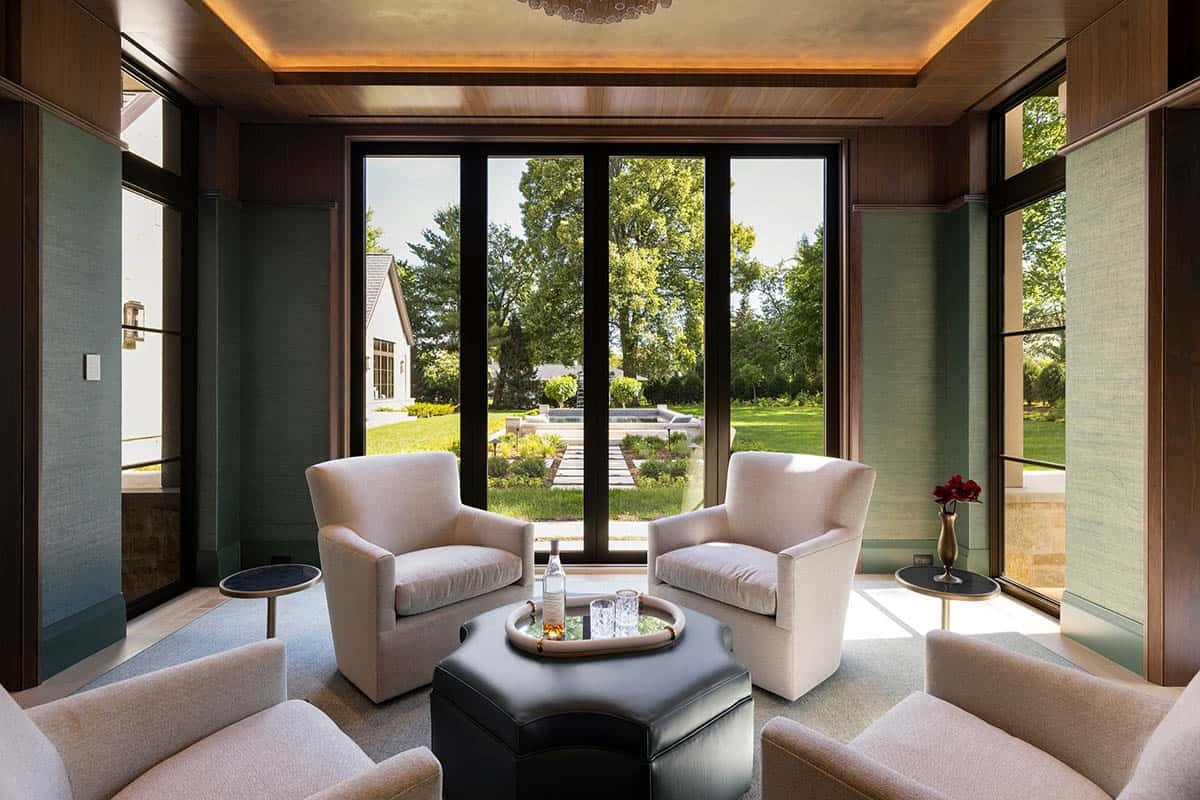 Wood-paneled lounge with garden view through black-framed doors