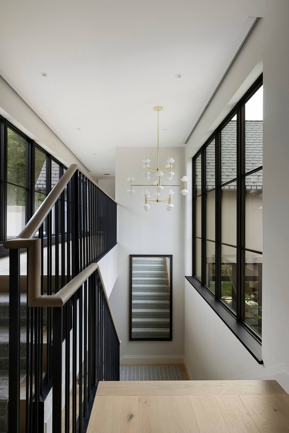 Staircase landing with brass chandelier and floor-length mirror