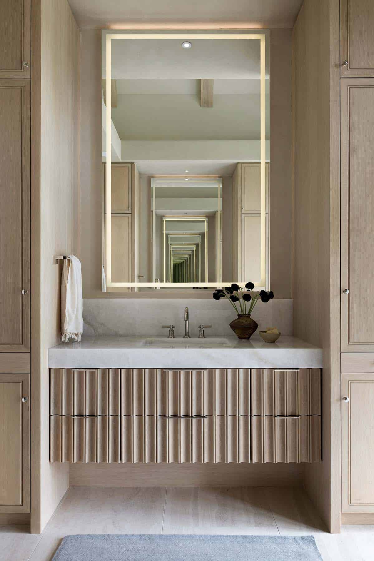 Fluted wood vanity with backlit mirror and infinity reflection