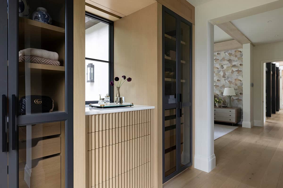 Closet vestibule with glass-front cabinets and mosaic wall beyond