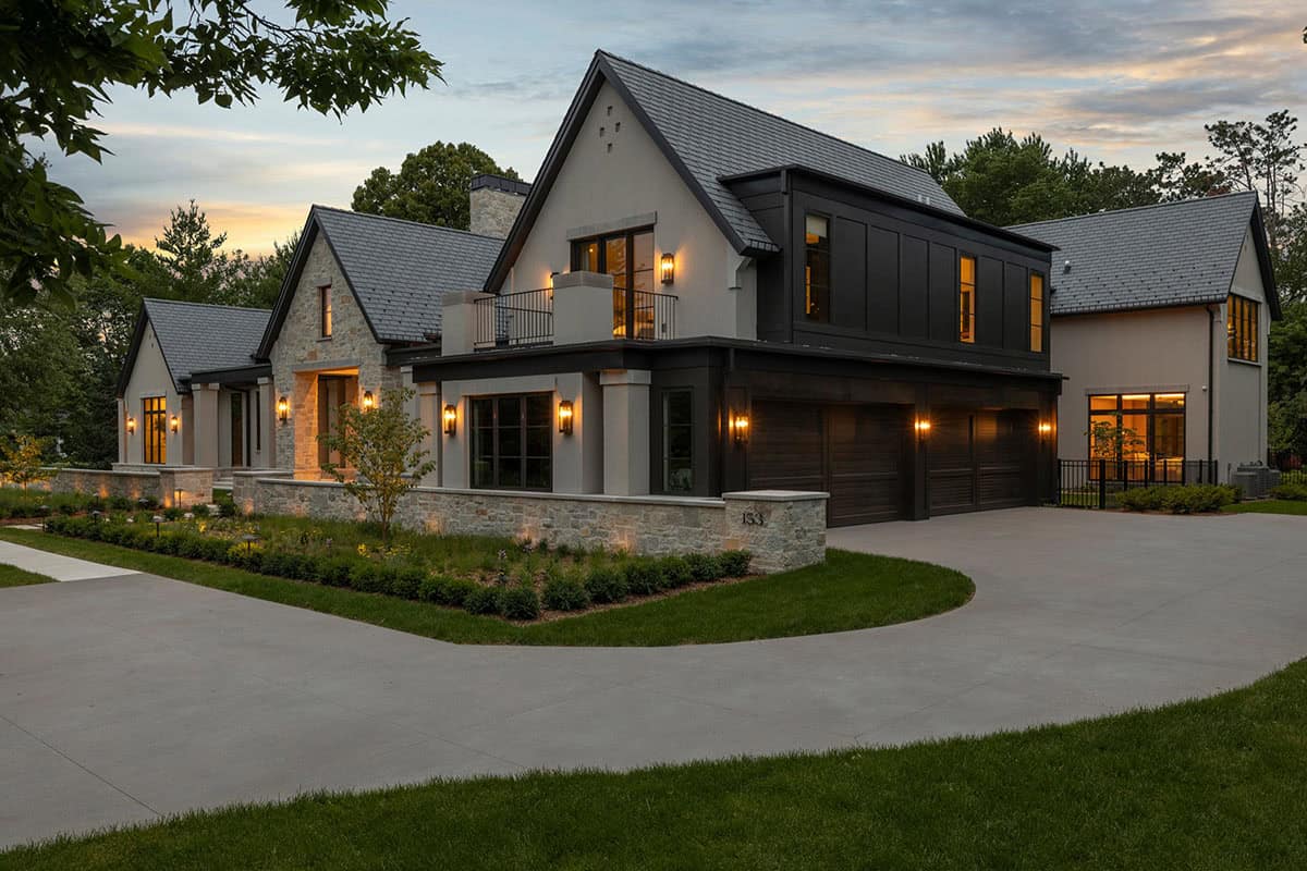 Dark wood garage doors and black paneled upper story at dusk