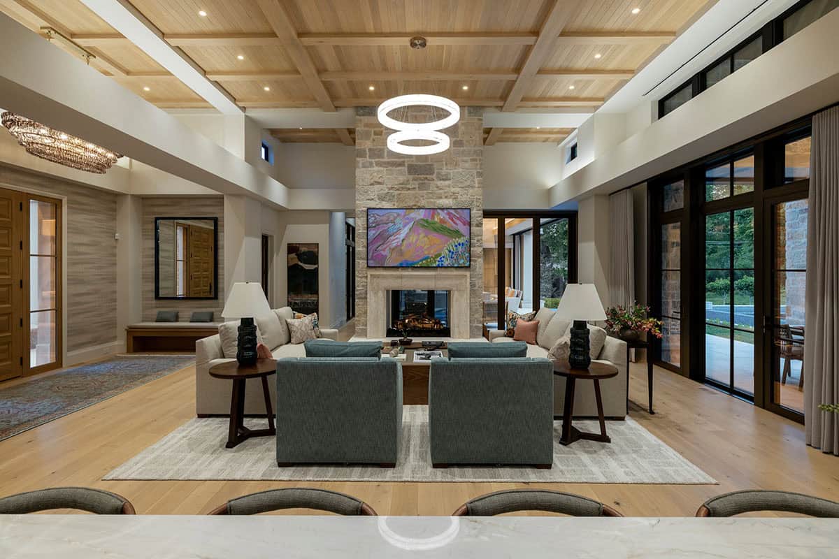 Living room with stone fireplace and layered chandeliers overhead