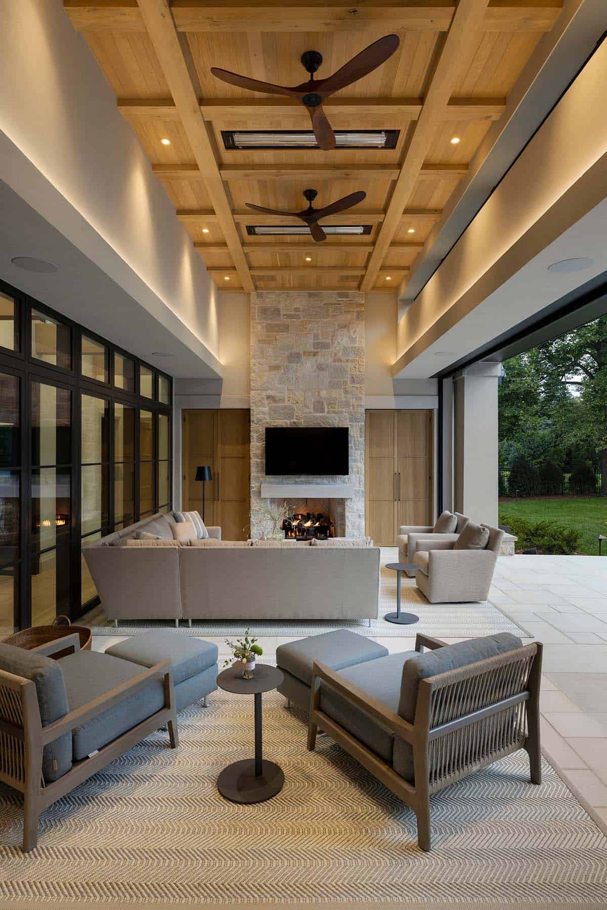 Outdoor living room with stone fireplace and dual ceiling fans