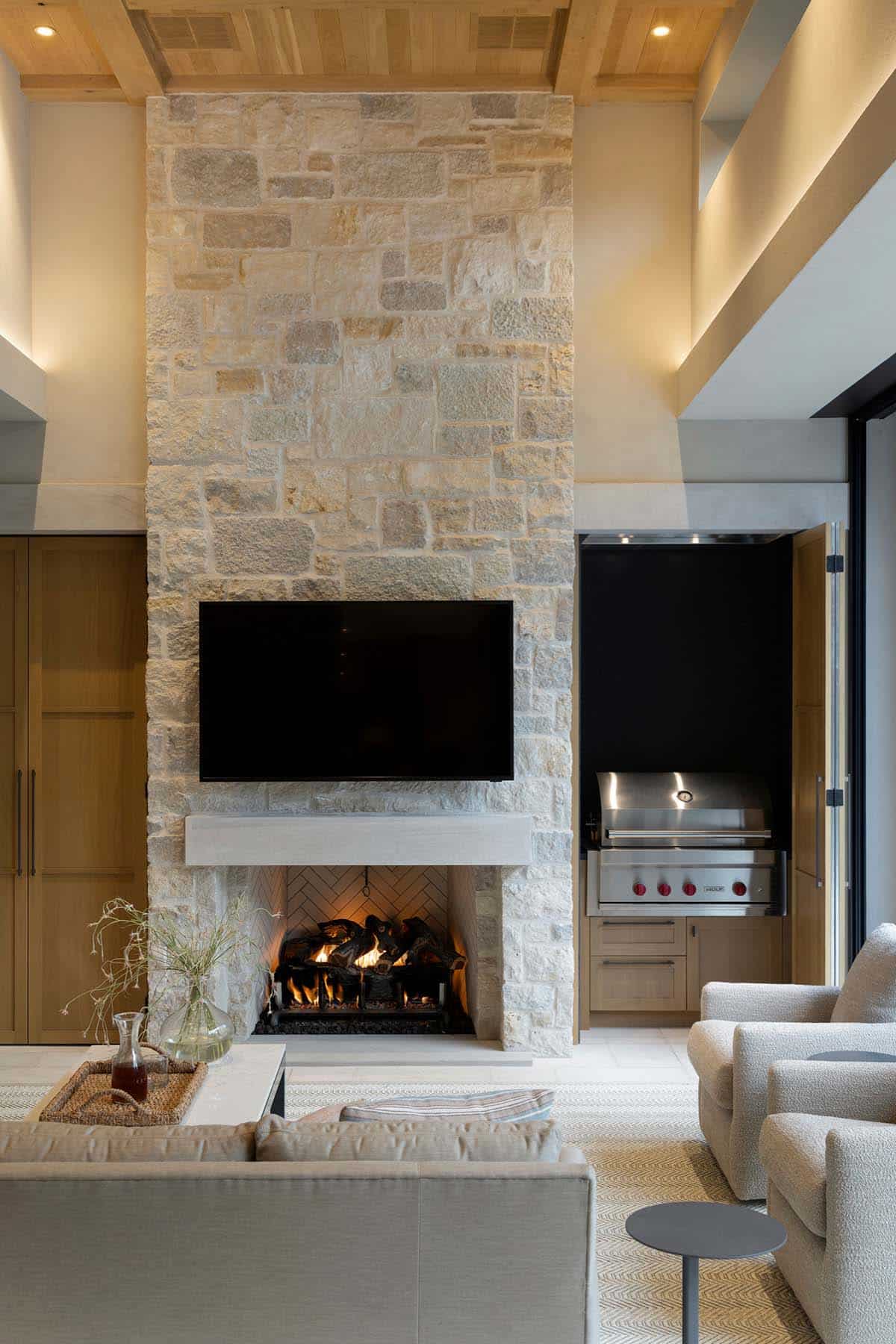 Stone fireplace with mounted television and adjacent outdoor grill