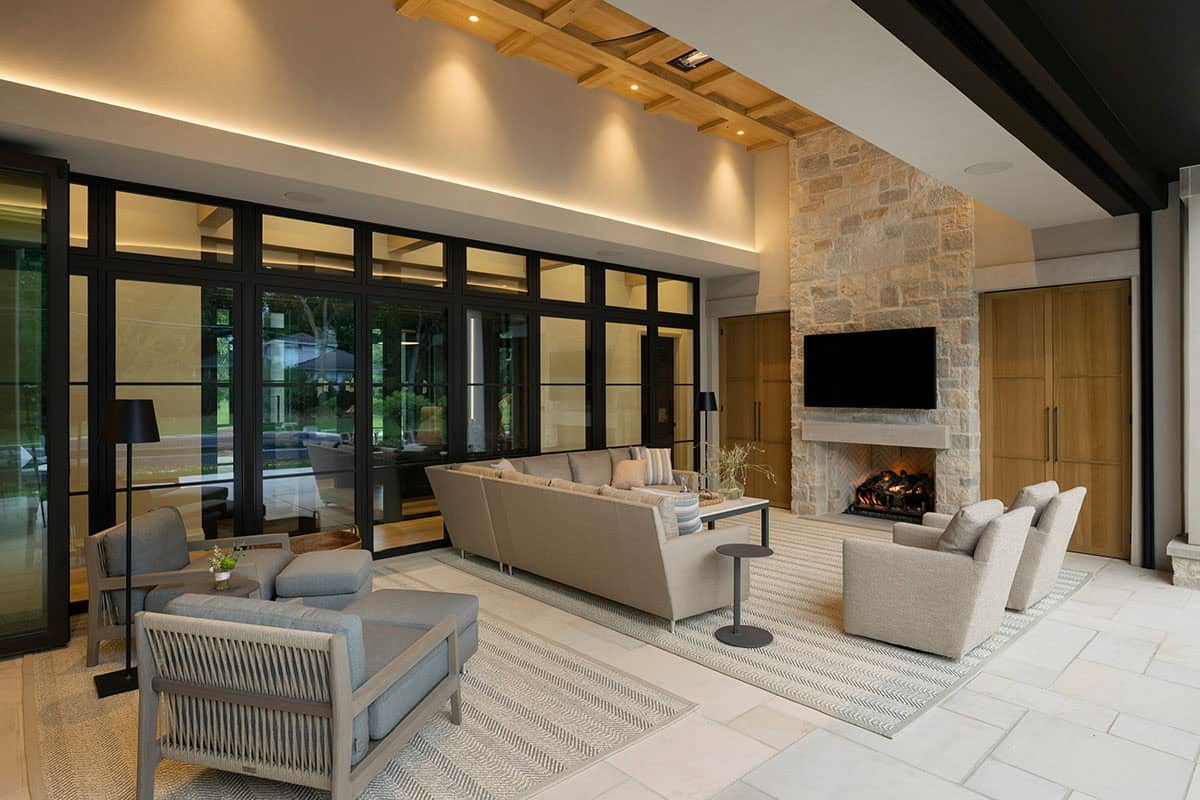 Outdoor lounge with woven chairs facing stone fireplace