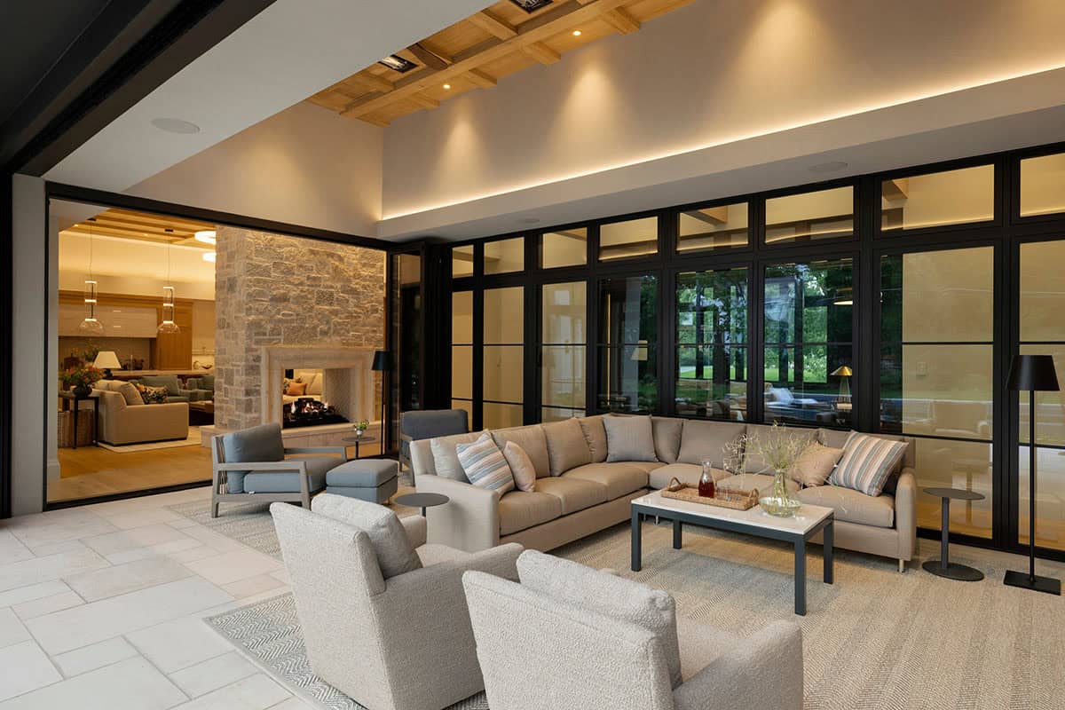 Covered patio sectional facing fireplace beside glass-walled interior