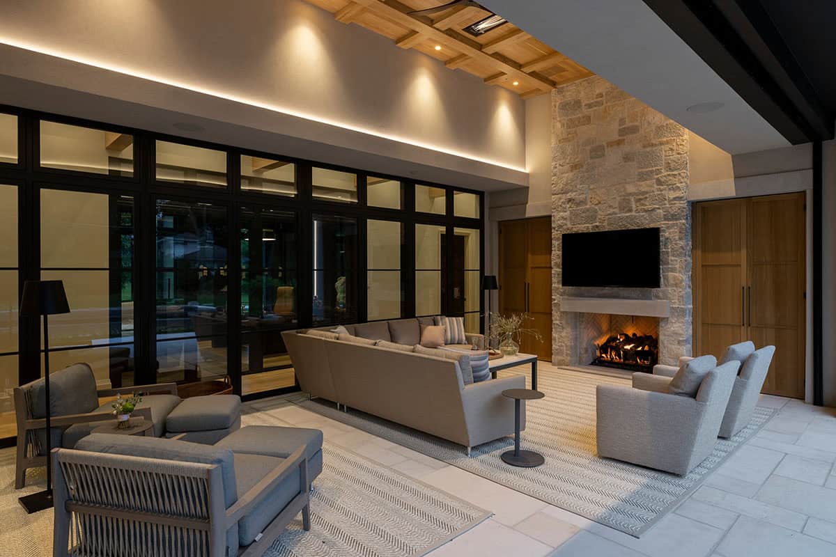 Outdoor seating area facing stone fireplace beneath wood beams