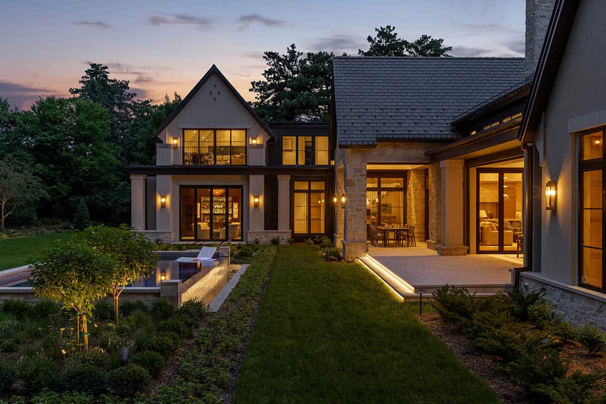 Backyard exterior glowing at dusk with pool and lit rooms