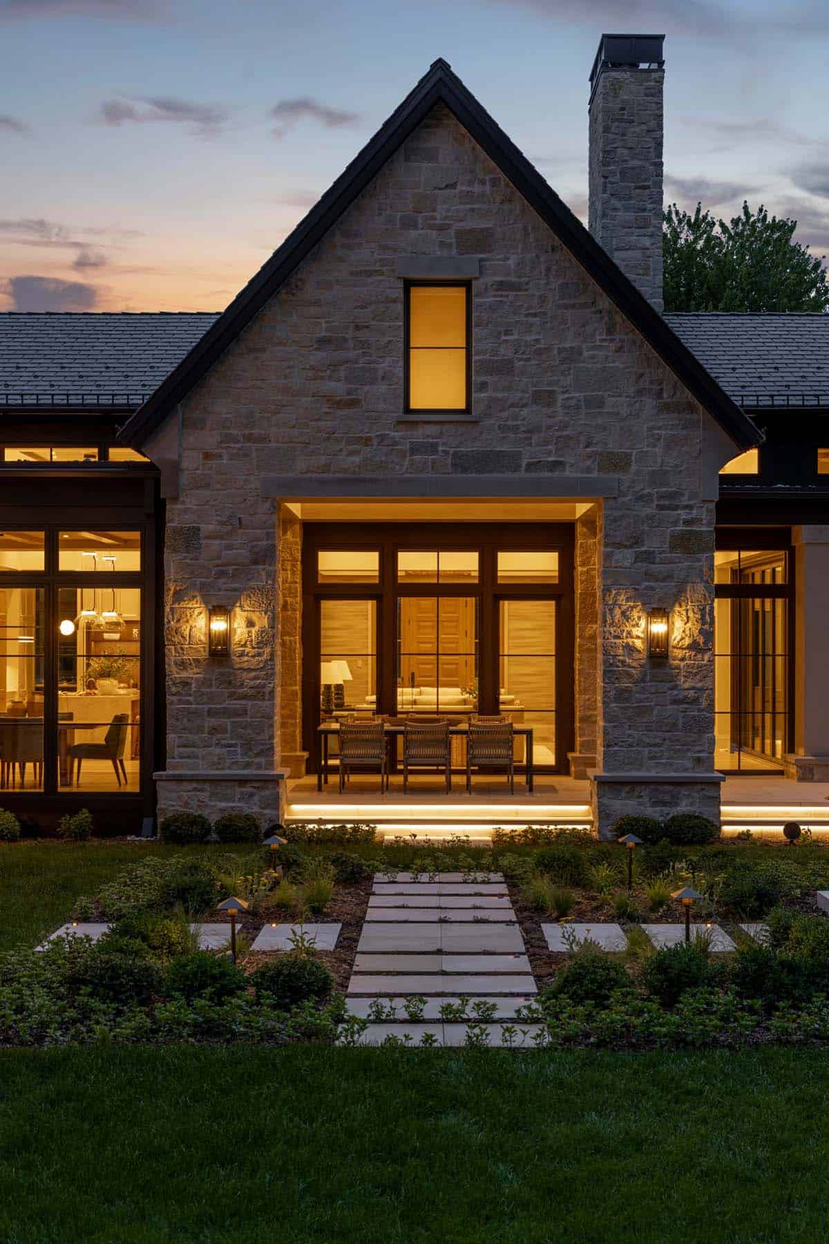 Stone gabled entry porch glowing warmly at dusk