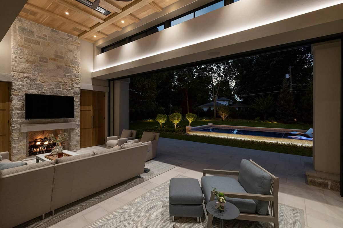 Covered patio opening to illuminated backyard pool at night