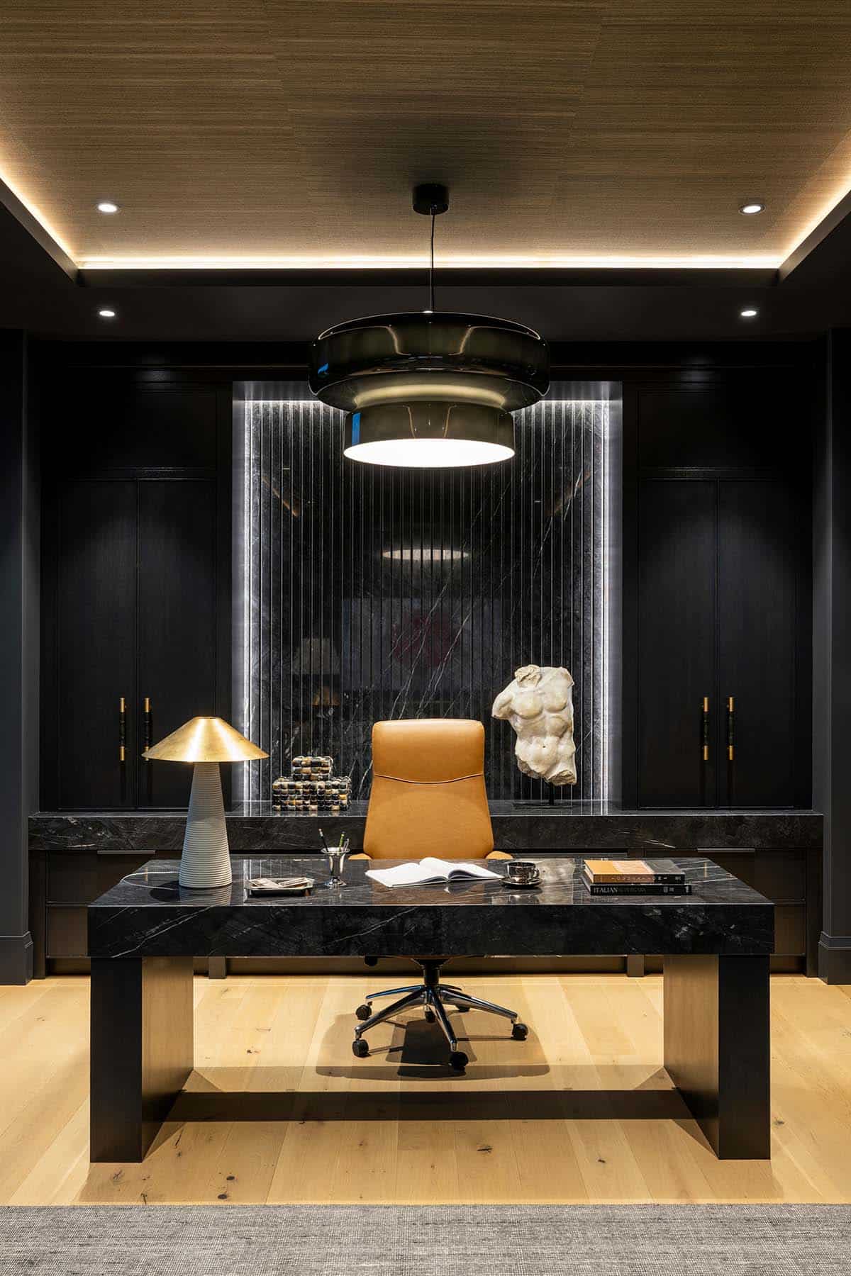 Home office desk with sculptural lamp and marble accent wall