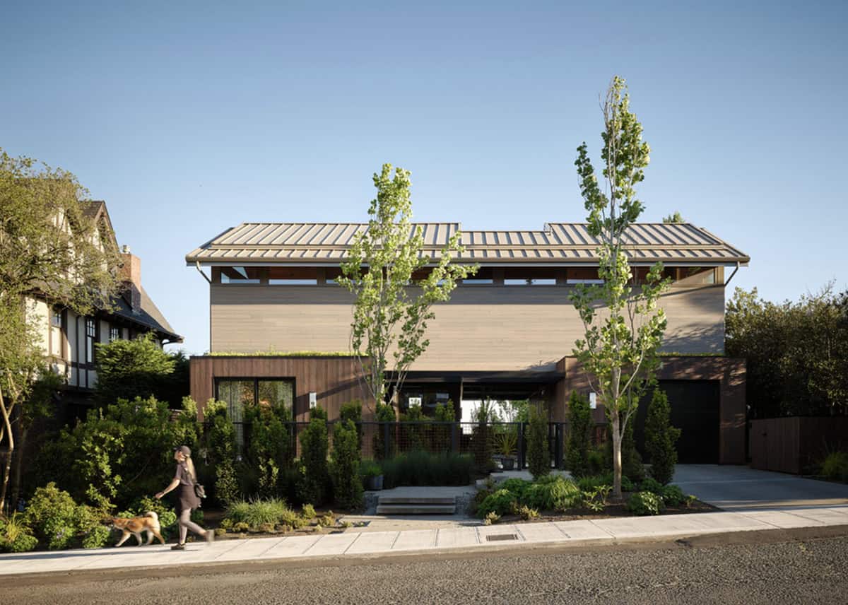 Modern wood-clad home exterior with corten steel entry and mature trees