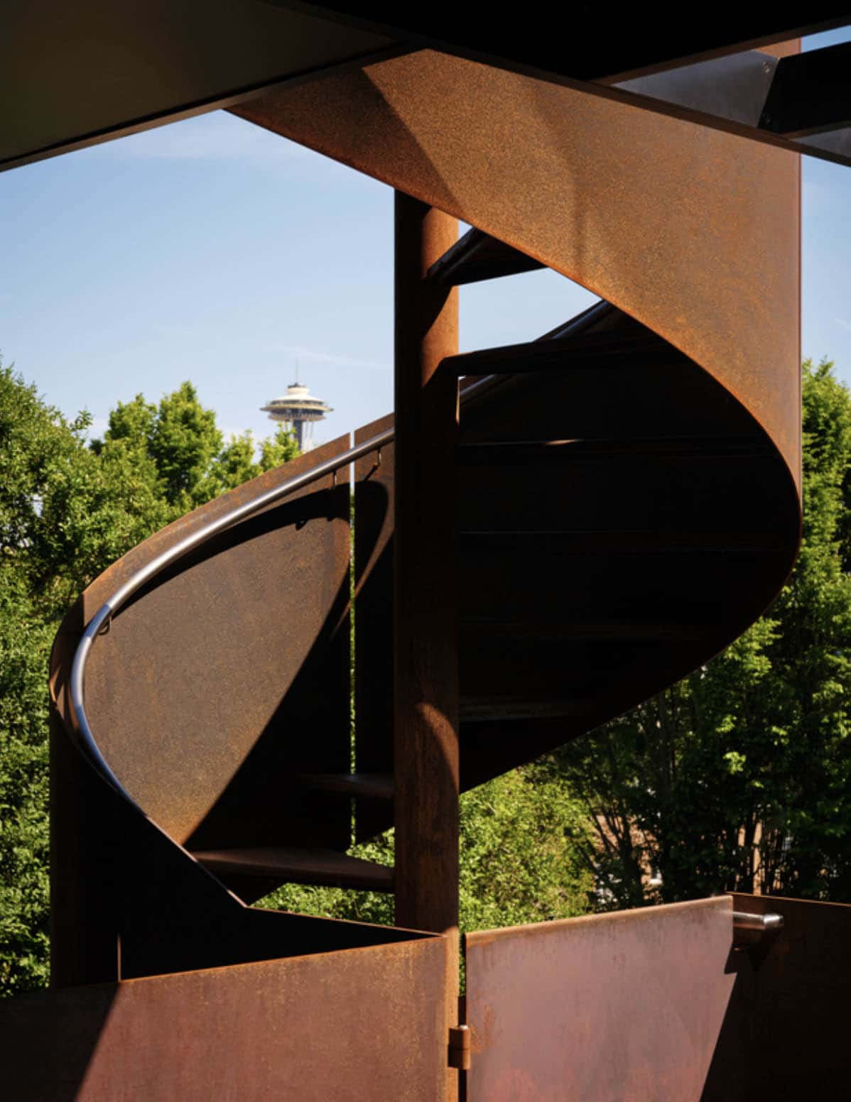Corten steel spiral staircase framed against Seattle skyline views