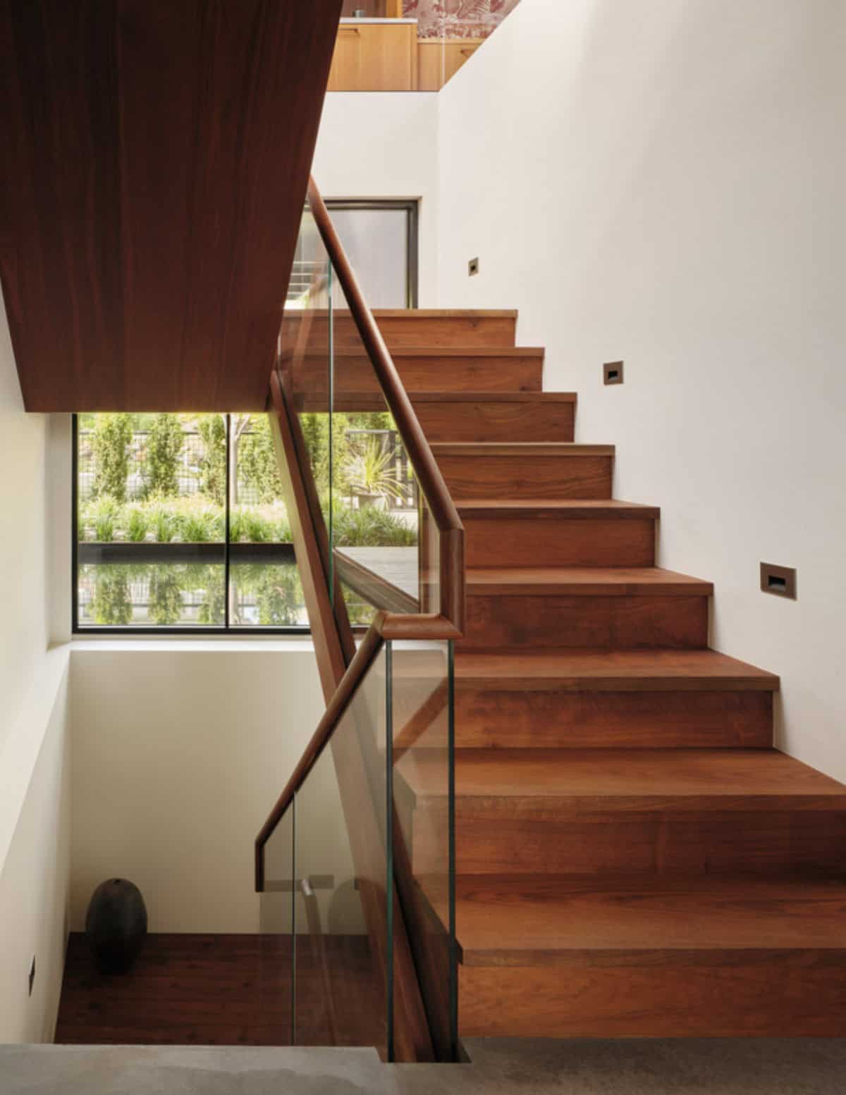 Walnut staircase with glass railing overlooking a sunken courtyard
