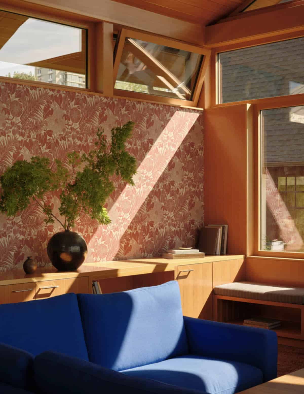 Sunlit reading nook with floral wallpaper and awning windows