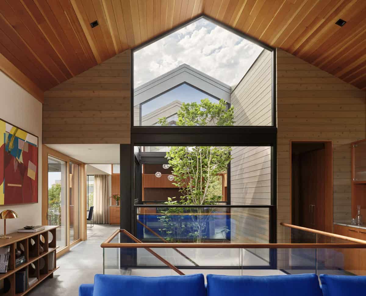 Double-height atrium framing a tulip tree beneath a gabled window