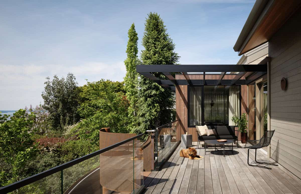 Rooftop deck with pergola, dog, and lounge seating among trees