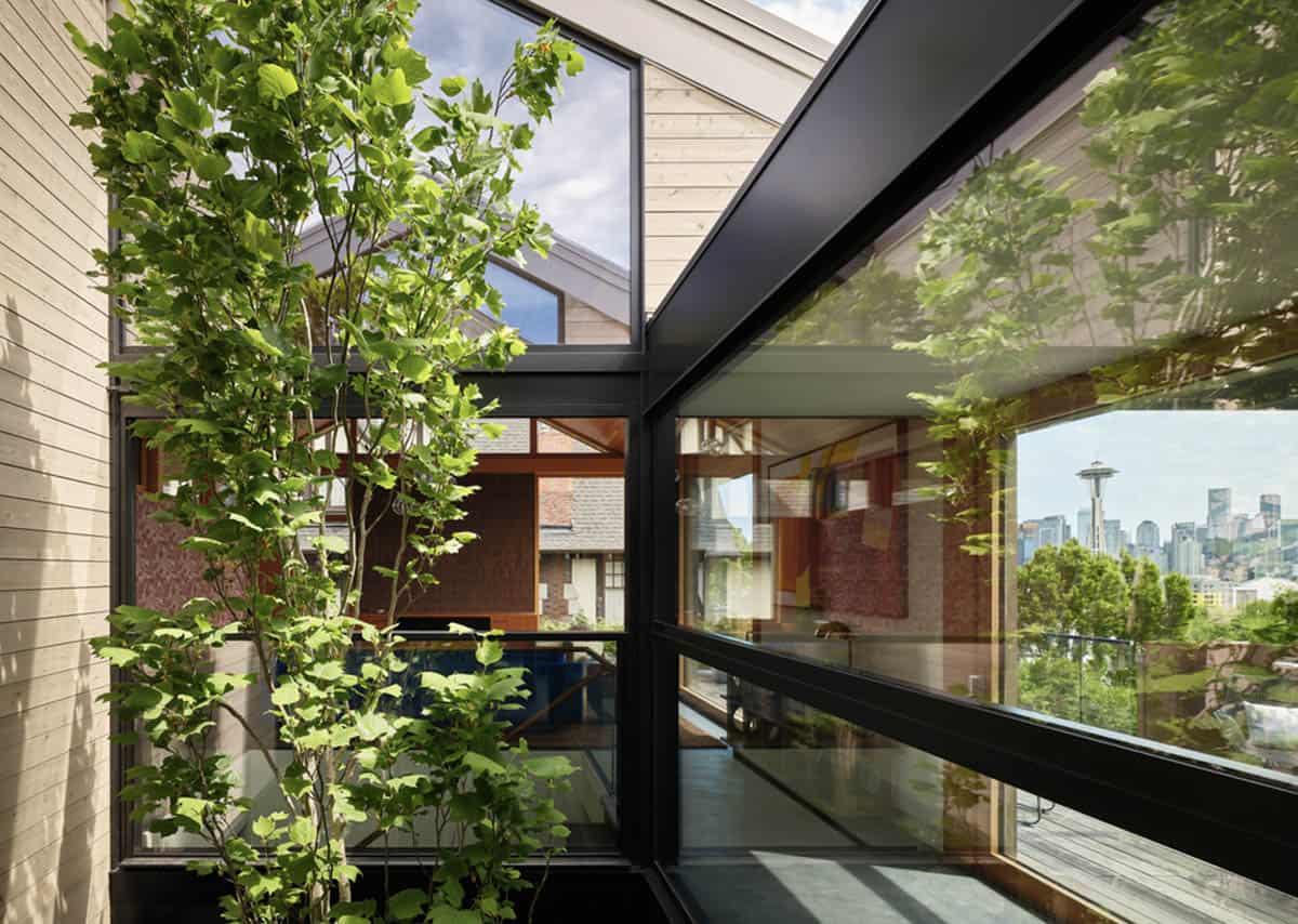 Glass atrium corner framing tulip tree leaves and Seattle skyline