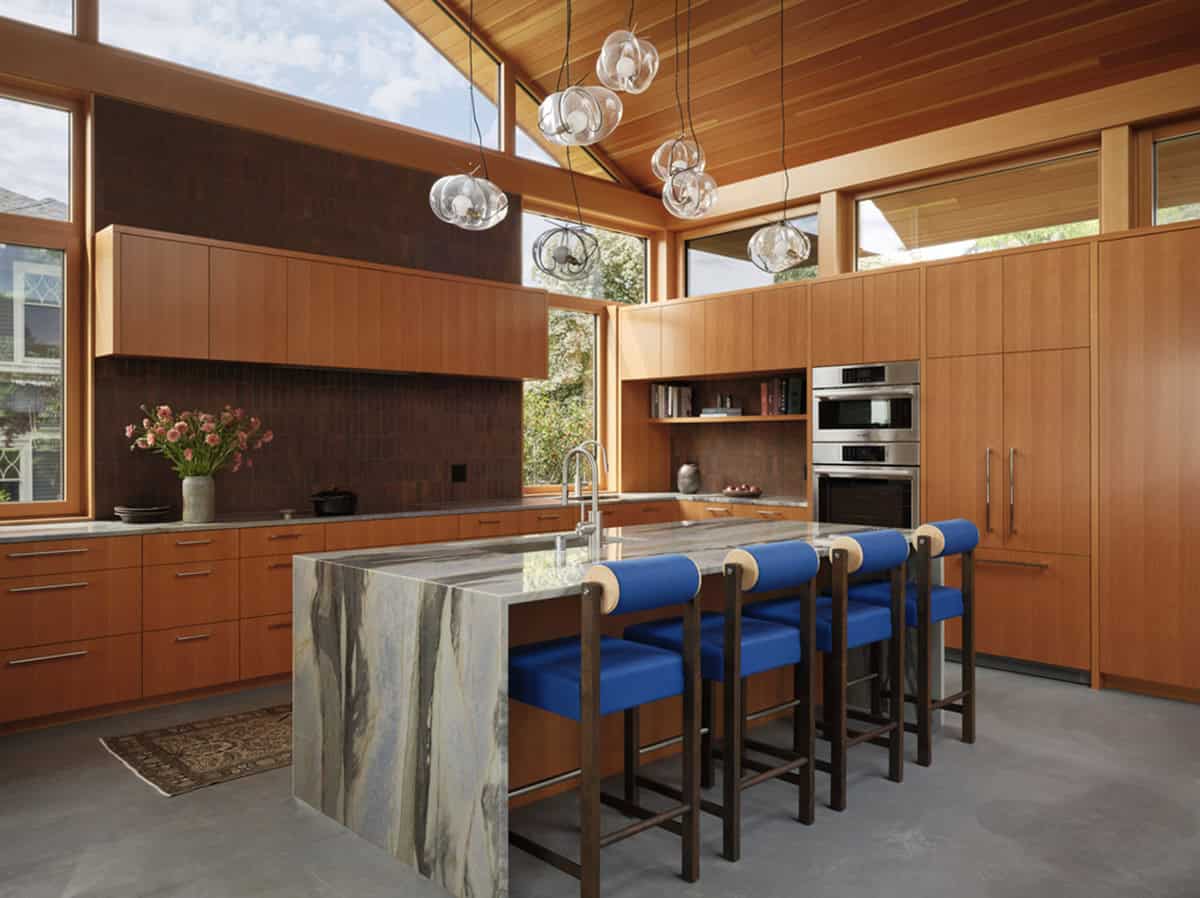 Vaulted wood kitchen with marble island and blue counter stools