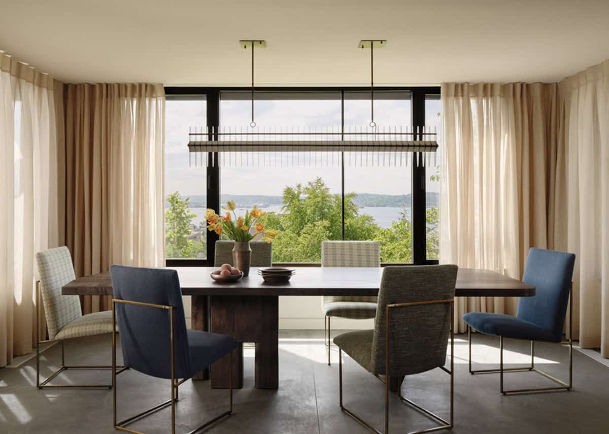 Dining room with sheer curtains framing water and hillside views