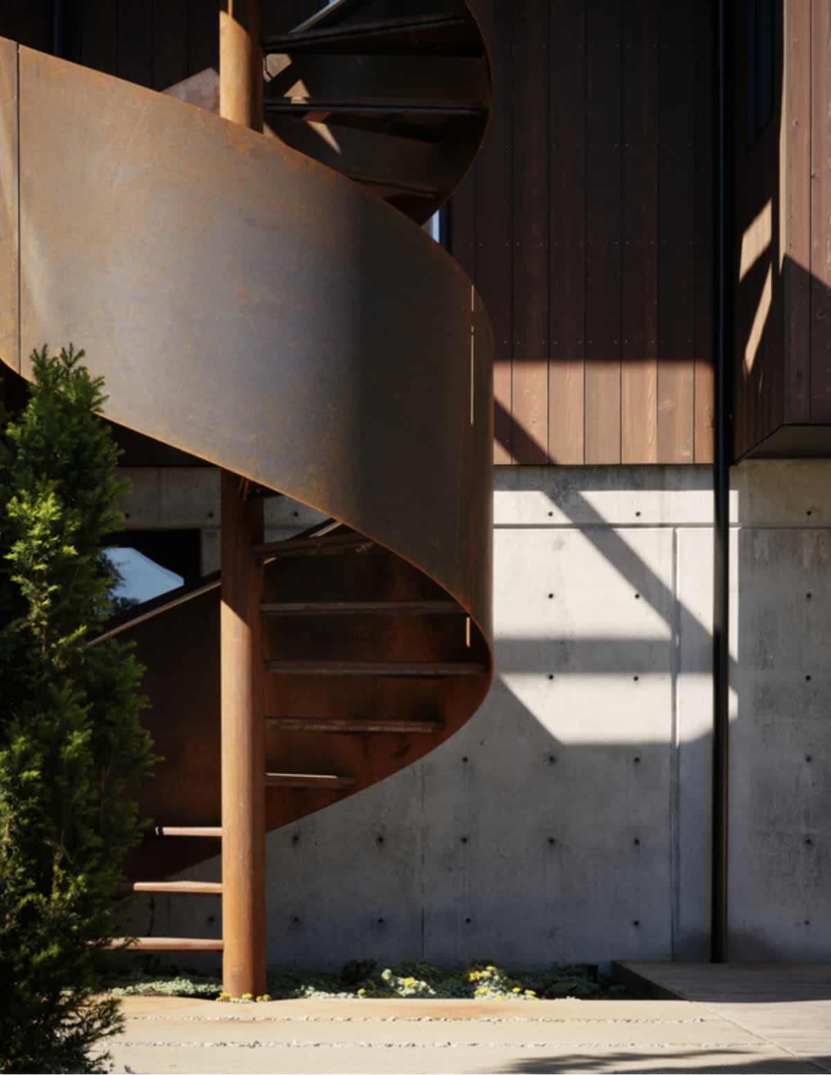 Corten steel stair and board-formed concrete beneath cedar siding