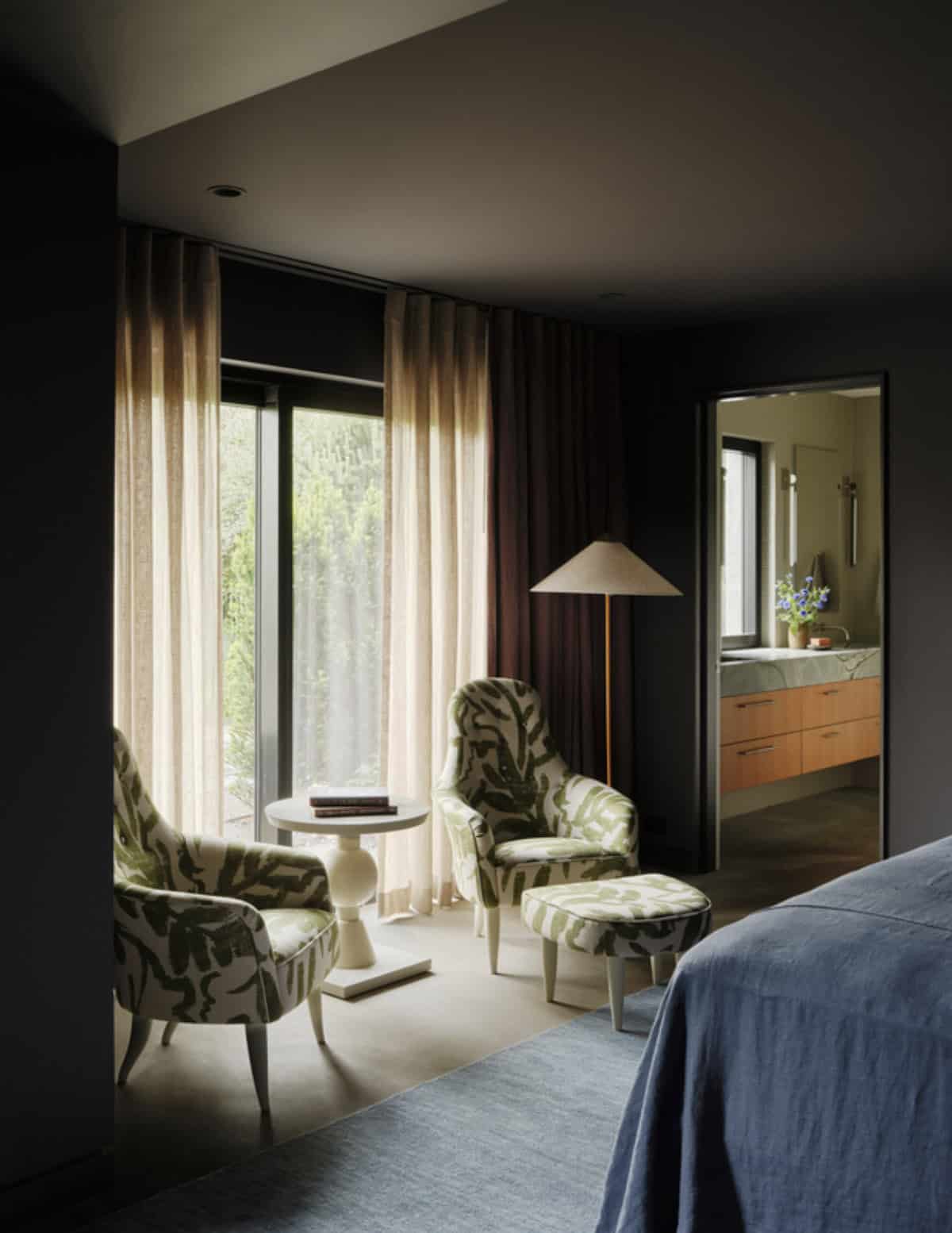 Reading nook with patterned armchairs beside sheer curtained windows