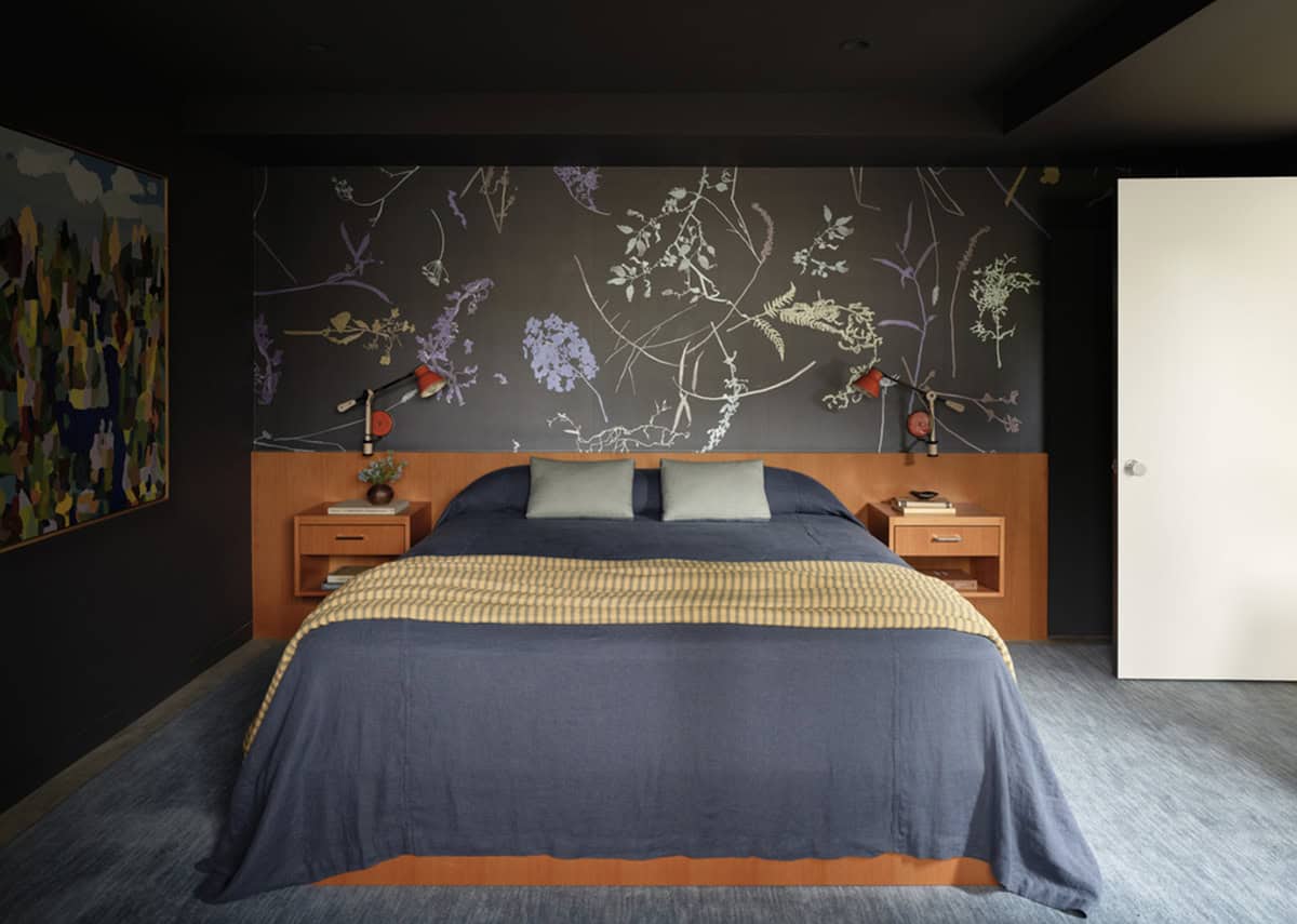 Primary bedroom with botanical wallpaper and warm wood nightstands