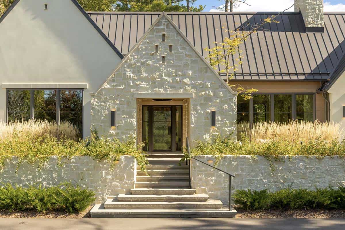 Stone gable entryway with wood door and iron handrail steps