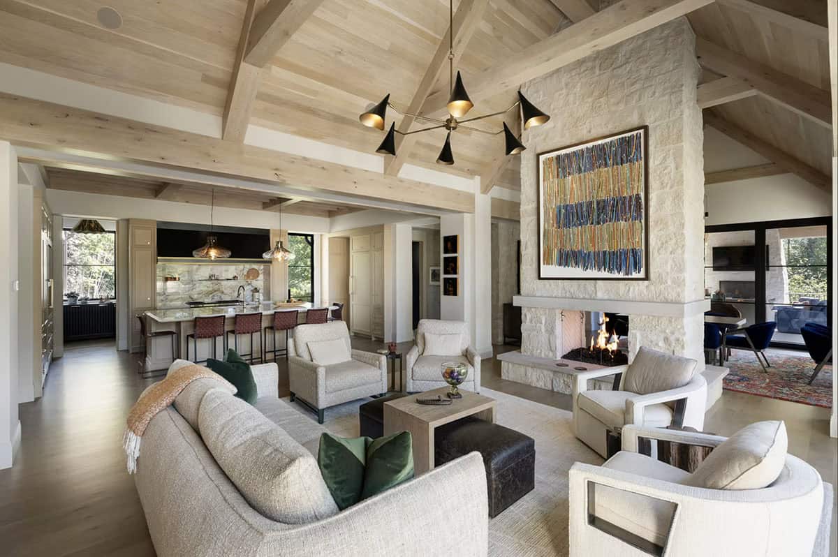Living room with stone fireplace and kitchen island beyond