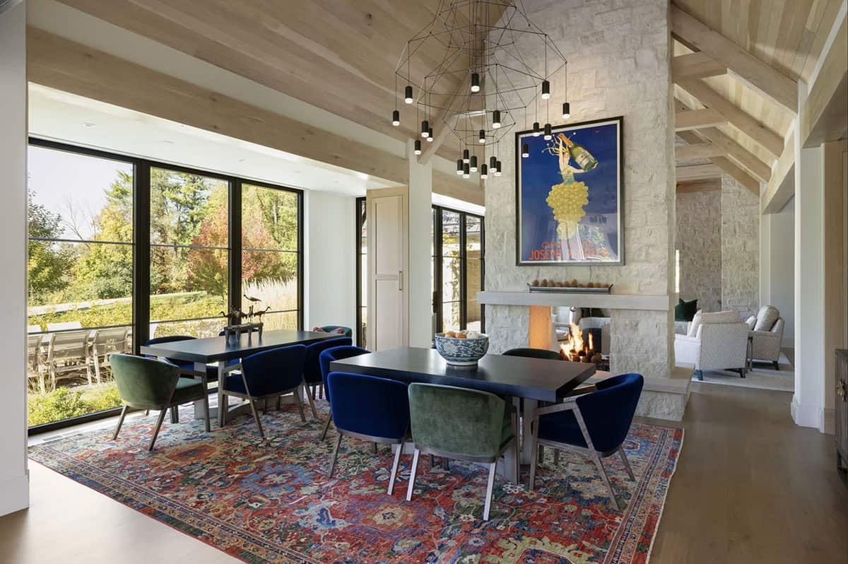 Dining room with velvet chairs, patterned rug, and vintage wine poster