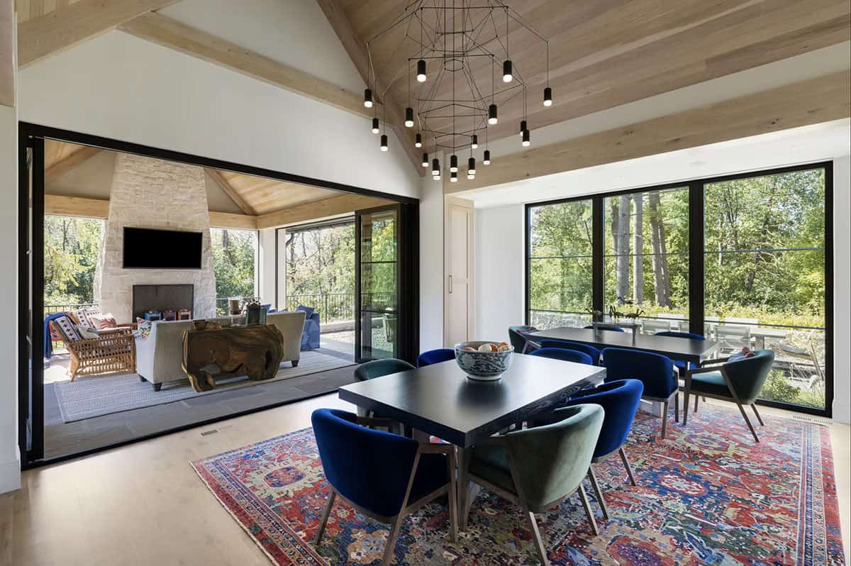 Dining room opening to covered porch with stone fireplace beyond