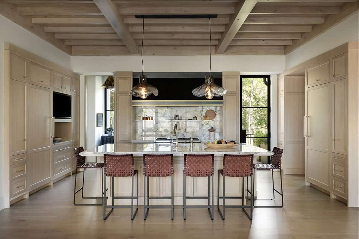 Kitchen island with woven leather stools and glass pendant lighting