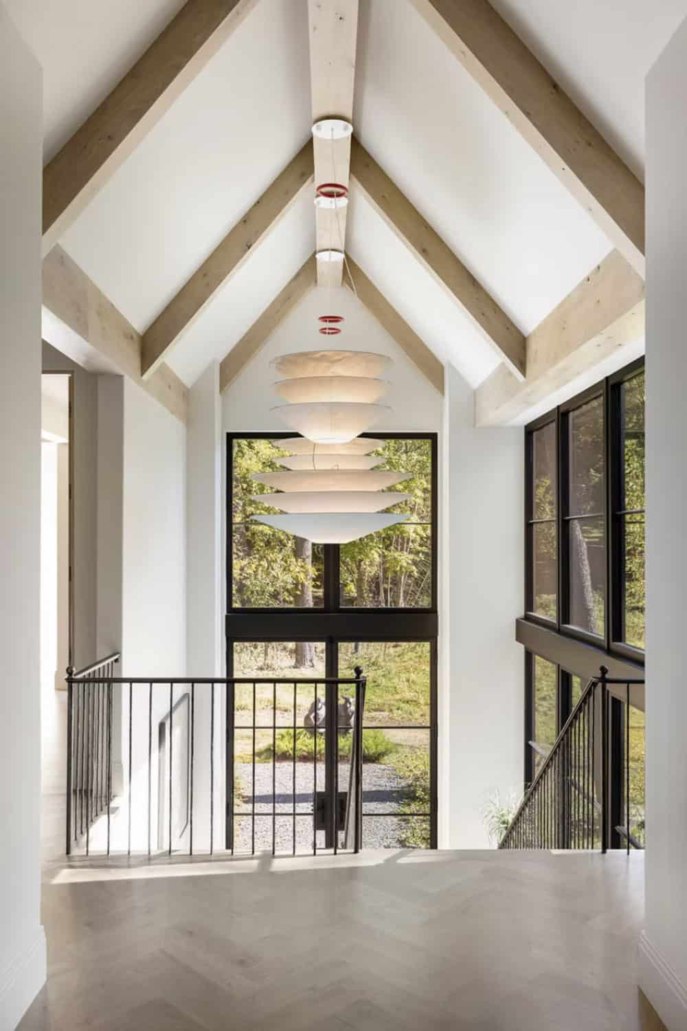 Vaulted hallway with tiered pendant light and floor to ceiling windows
